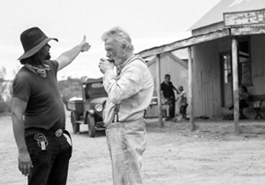 Behind the scenes shot from Sweet Country - two men in the foreground and a building in the background