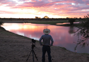 Gun Ringer - a man looking off into the sunset with camera equipment next to him